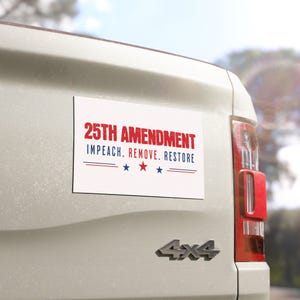May include: A white rectangular bumper sticker with the text "25TH AMENDMENT" in red, and "IMPEACH. REMOVE. RESTORE" in smaller text. Below are three blue stars and a blue line. The sticker is affixed to the back of a vehicle.