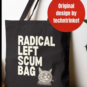 Puede incluir: Bolso tote negro con la frase "RADICAL LEFT SCUM BAG" en letras blancas. Debajo, una ilustración detallada de un gato fumando. Un círculo rojo en la esquina dice "Original design by techntrinket".