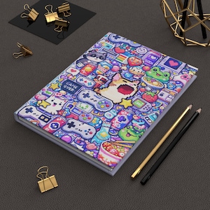 May include: A colorful notebook with a pixelated video game design featuring controllers, food, and characters. The cover is a vibrant mix of blues, purples, and pinks, with the words "GAME OVER" visible. Gold and black pencils and paper clips are also present.