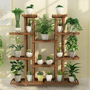 May include: A multi-tiered, wooden plant stand filled with various potted plants. The stand is stained a warm brown and features multiple shelves of varying sizes. The plants include ferns, succulents, and other greenery in white pots, creating a natural display.