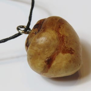 Op de afbeelding: Een houten hanger met een natuurlijk houtnerfpatroon en een donkerbruin koord.