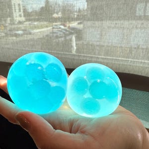 Può includere: Due sfere blu traslucide con sfere blu più piccole all'interno. Le sfere sono circa delle dimensioni di una palla da golf.