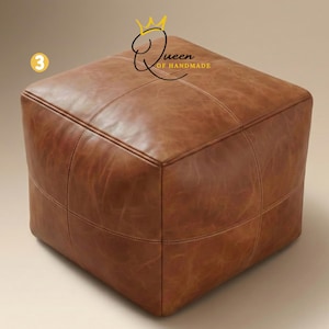 May include: A square, brown leather ottoman with stitched detailing. The ottoman has a cube shape and is made of a rich, textured leather. The text "Queen of Handmade" is visible on the top right corner.