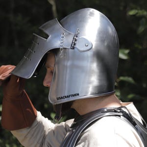 Pu&ograve; includere: Un elmo da cavaliere in acciaio lucido con visiera incernierata, fessure orizzontali per gli occhi e fori di ventilazione. Sul lato dell'elmo &egrave; presente la scritta USACRAFTMEN. Una piccola catena metallica collega la visiera all'elmo.