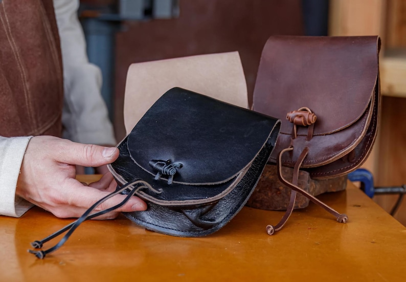Puede incluir: Tres bolsas de cuero con correas y hebillas de diferentes colores. Las bolsas son de cuero marr&oacute;n, negro y beige.