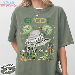 Puede incluir: Camiseta verde musgo con un gráfico colorido de personajes de Disney celebrando el Día de San Patricio en Epcot. El diseño incluye Mickey y Minnie Mouse, Donald y Daisy Duck, Goofy y Pluto. La palabra "EPCOT" se muestra en verde y oro.