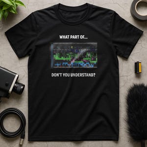 May include: Black t-shirt with the text "WHAT PART OF... DON'T YOU UNDERSTAND?" above and below a graphic of a video editing timeline. The shirt is made of a soft material.