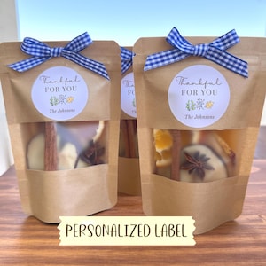 May include: Two brown kraft paper pouches with clear windows containing dried orange slices, cinnamon sticks, and star anise. Each pouch features a blue and white gingham ribbon bow and a round label reading Thankful FOR YOU The Johnsons.