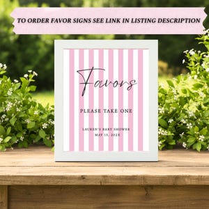 May include: A white framed sign featuring a pink and white vertical striped background. The text reads "Favors", "PLEASE TAKE ONE", "LAUREN'S BABY SHOWER", and "MAY 15, 202X". The top banner text reads "TO ORDER FAVOR SIGNS SEE LINK IN LISTING DESCRIPTION".