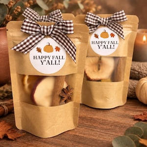 May include: Two brown kraft paper pouches with clear windows containing dried fruit slices, cinnamon sticks, and star anise. Each pouch features a white circular label with a pumpkin, leaves, and the text HAPPY FALL Y'ALL! topped with a brown gingham bow.
