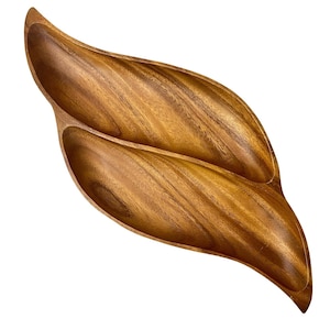 Op de afbeelding: Een houten serveerschaal met twee secties, gevormd als een blad. De schaal is gemaakt van donkerbruin hout met een natuurlijke houtnerf.