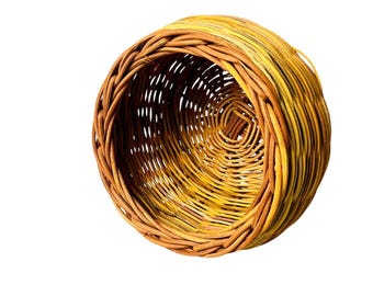 May include: A round, woven basket made of natural materials. The basket is brown and yellow and has a natural, rustic look.