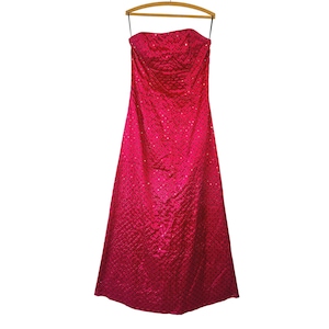May include: A floor-length, strapless magenta gown featuring a textured, quilted diamond pattern across the entire fabric. The dress has a fitted bodice that transitions into a full-length skirt, with small, reflective accents embedded within the grid.