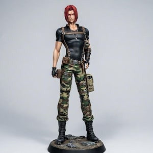 May include: A detailed figurine of a character with red hair, wearing a black shirt, camouflage pants, and black boots. The figure has a serious expression and is posed on a rocky base. Accessories include a necklace, belt, and pouches.
