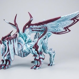 May include: A detailed sculpture of a mythical creature with large, textured wings. The figure is primarily light blue with burgundy accents, featuring intricate patterns and a dynamic pose. The creature has a quadruped stance and is highly detailed.