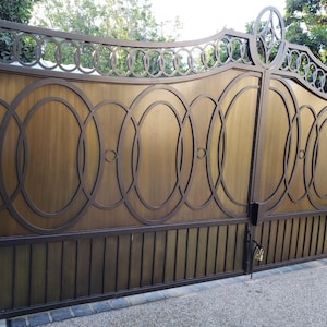 May include: A double gate made of metal with a decorative design of overlapping circles. The gate is painted a dark brown color and has a brushed metal finish.