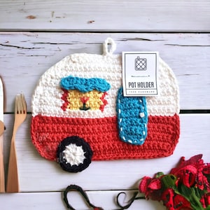 May include: Crocheted pot holder shaped like a red and white camper with a blue door and a yellow window. The pot holder has a white tag that says "Pot Holder 100% Handmade".