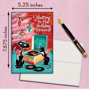 May include: A holiday greeting card, 5.25 inches wide and 7.875 inches tall, featuring a retro design with black cats, a record player, and the text "Getting In The Holiday Groove!". Includes a white envelope and a fountain pen.
