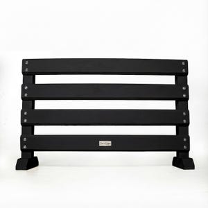 May include: A black wooden bench with four horizontal slats and two supporting legs. The bench is painted black and has silver hardware. The bench has a rectangular shape and is suitable for outdoor or indoor use.
