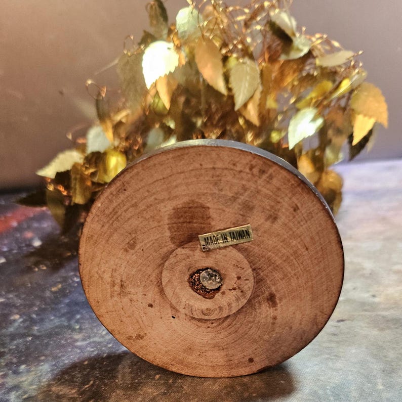May include: A gold-colored metal tree with a wooden base. The base has a label that reads "Made in Taiwan".
