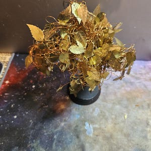 May include: A gold wire tree sculpture with gold leaf leaves. The tree is on a black base.