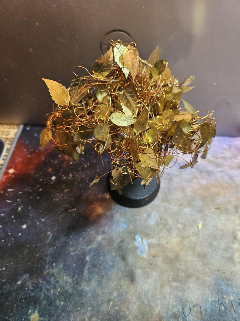 May include: A gold wire tree sculpture with gold leaf leaves. The tree is on a black base.