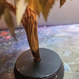 May include: A gold leaf tree sculpture with a brown wire trunk and a black circular base.