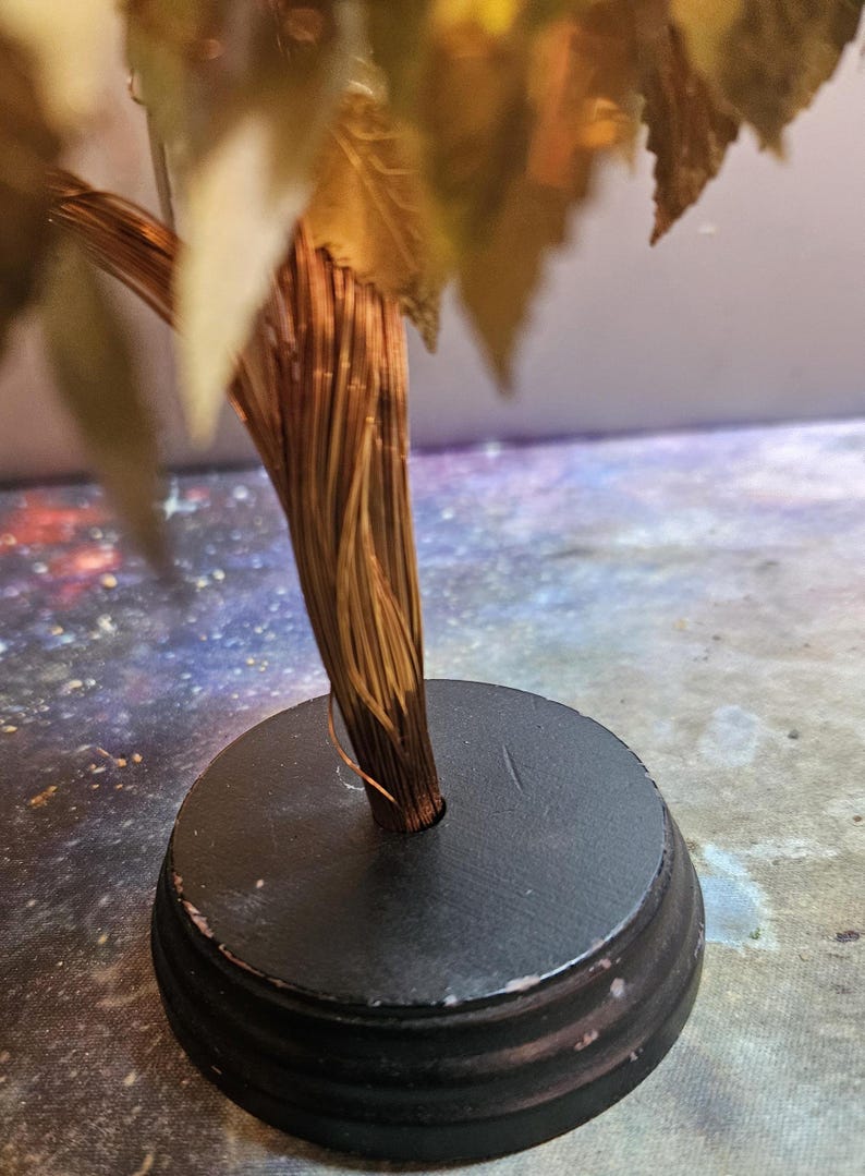 May include: A gold leaf tree sculpture with a brown wire trunk and a black circular base.