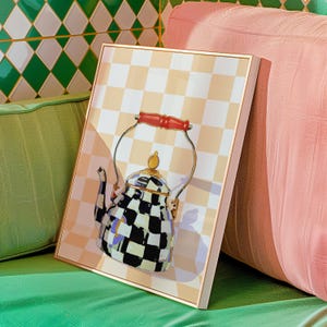 May include: A black and white checkered teapot with a red handle sits on a peach and white checkered background.