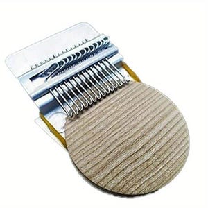 Peut inclure: Un outil de reprisage composé d'un disque en bois circulaire avec une texture de grain de bois brun clair. Sur le dessus est fixé un mécanisme en métal argenté doté d'une série de crochets en fil parallèle et d'une plaque pour tendre le tissu.