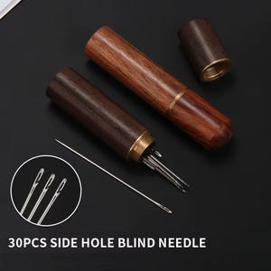 Op de afbeelding: Houten naaldenkoker met messing accenten, met meerdere naalden. De cilindrische koker heeft een schroefdop. De tekst "30PCS SIDE HOLE BLIND NEEDLE" is zichtbaar onderaan de afbeelding.