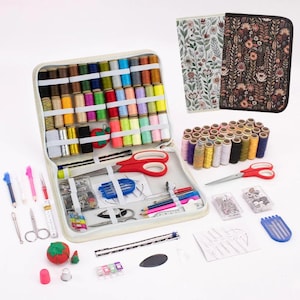 Könnte beinhalten: Ein Nähset mit einer Vielzahl von farbigen Garnrollen, Nadeln, Scheren und anderem Nähzubehör. Das Set enthält ein Etui mit Reißverschluss und zwei dekorative Stoffbezüge mit floralen Mustern.