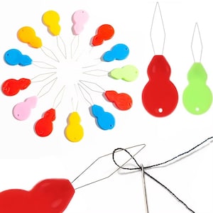 Puede incluir: Una colección de enhebradores de agujas coloridos en varios tonos, incluyendo rojo, amarillo, azul, rosa y verde. Cada enhebrador tiene un pequeño mango en forma de lágrima y un fino lazo de alambre para facilitar el enhebrado. La imagen también muestra una aguja siendo enhebrada.