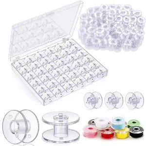 May include: A clear plastic sewing bobbin organizer with a hinged lid, filled with numerous clear bobbins. Additional bobbins are scattered around the organizer. Several spools of thread in various colors are also visible.