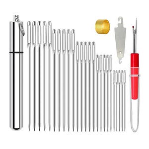 Peut inclure: Un kit de couture avec divers outils. Il comprend un étui à aiguilles argenté, plusieurs aiguilles argentées de différentes longueurs, un dé à coudre doré, un découseur argenté et un découseur à manche rouge.