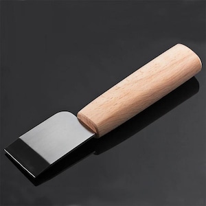 May include: A stainless steel scraper with a rectangular blade and a light-coloured wooden handle. The handle is cylindrical and appears to be made of a light-coloured wood. The blade is a shiny silver colour.