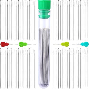 May include: A clear plastic tube filled with a large quantity of silver sewing needles. The tube has a green lid and is surrounded by rows of needles.