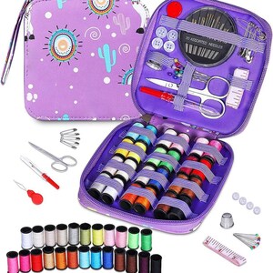 Puede incluir: Un kit de costura morado con cremallera, con un diseño de llama y cactus. El kit contiene carretes de hilo, agujas, tijeras, botones y otros suministros de costura. El kit está abierto, mostrando el contenido organizado.