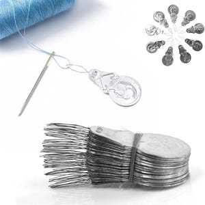 May include: A collection of silver-toned metal needle threaders with a circular handle design. The set includes a spool of light blue thread, a single sewing needle, and a stacked bundle of multiple threaders held together by a thin elastic band.