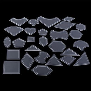 Könnte beinhalten: Eine Sammlung klarer Acryl-Quiltschablonen in verschiedenen geometrischen Formen, darunter Herzen, Sechsecke und Dreiecke. Jede Schablone hat eine silberne Umrandung und ist für Stoffzuschnitte und Quiltprojekte konzipiert. Auf schwarzem Hintergrund.