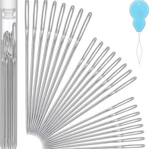 May include: A collection of silver sewing needles with large eyes, displayed in a clear plastic tube with a white cap. A light blue needle threader is also included, with a diamond-shaped wire loop.