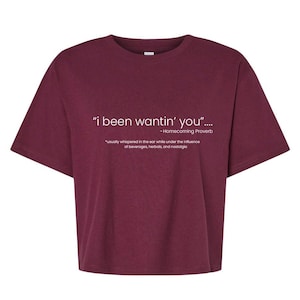 Puede incluir: Una camiseta de manga corta color granate con texto blanco que dice "i been wantin' you".... -Homecoming Proverb *usually whispered in the ear while under the influence of beverages, herbals, and nostalgia. La camiseta tiene cuello redondo.