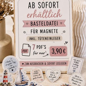Puede incluir: Un letrero rectangular de madera con fondo blanco y detalles en rosa que muestra texto en alemán sobre un archivo de manualidades digital para imanes, incluyendo siete archivos PDF e insertos, rodeado de varios recortes de papel con temas náuticos.