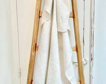 May include: A white linen throw blanket draped over a wooden ladder.