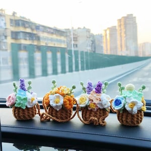 May include: Four crocheted flower arrangements in small brown baskets with handles. The baskets are filled with colorful crocheted flowers, including white, yellow, orange, purple, and green.