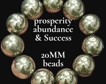 May include: A circular arrangement of eleven large, reflective, metallic-toned spherical beads. The center of the image features the white text "prosperity abundance & Success" followed by "20MM beads" below it, all set against a solid black background.
