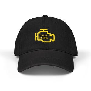 May include: Black baseball cap featuring a yellow graphic of a car engine with the words "CHECK ENGINE". The cap has a curved brim and a structured fit, suitable for casual wear.