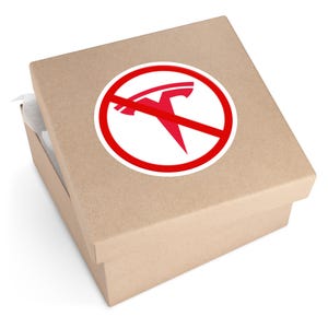 May include: A brown cardboard box with a white and red sticker. The sticker features a red Tesla logo inside a red circle with a red line through it, indicating a prohibition. The box is partially open, revealing white tissue paper.