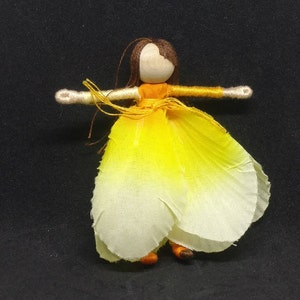 May include: A handmade doll with brown hair, a yellow and white dress, and orange yarn arms and legs.