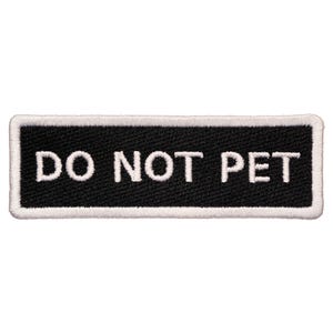 Puede incluir: Parche bordado en blanco y negro con texto blanco que dice "DO NOT PET" sobre un fondo negro.